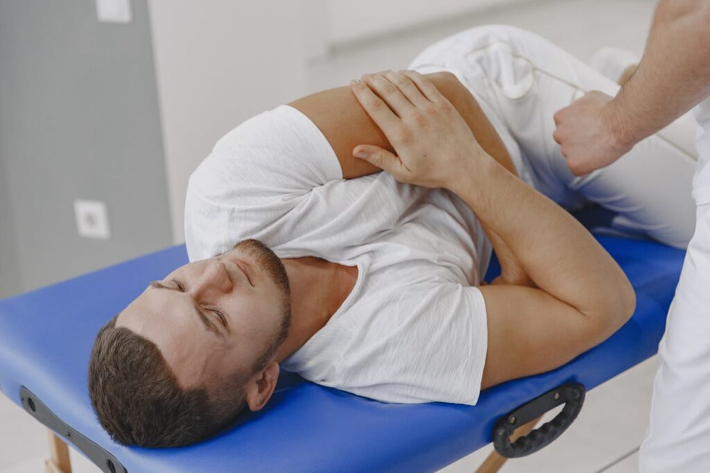 A man undergoing a therapeutic massage session on a blue massage table in a clinic.